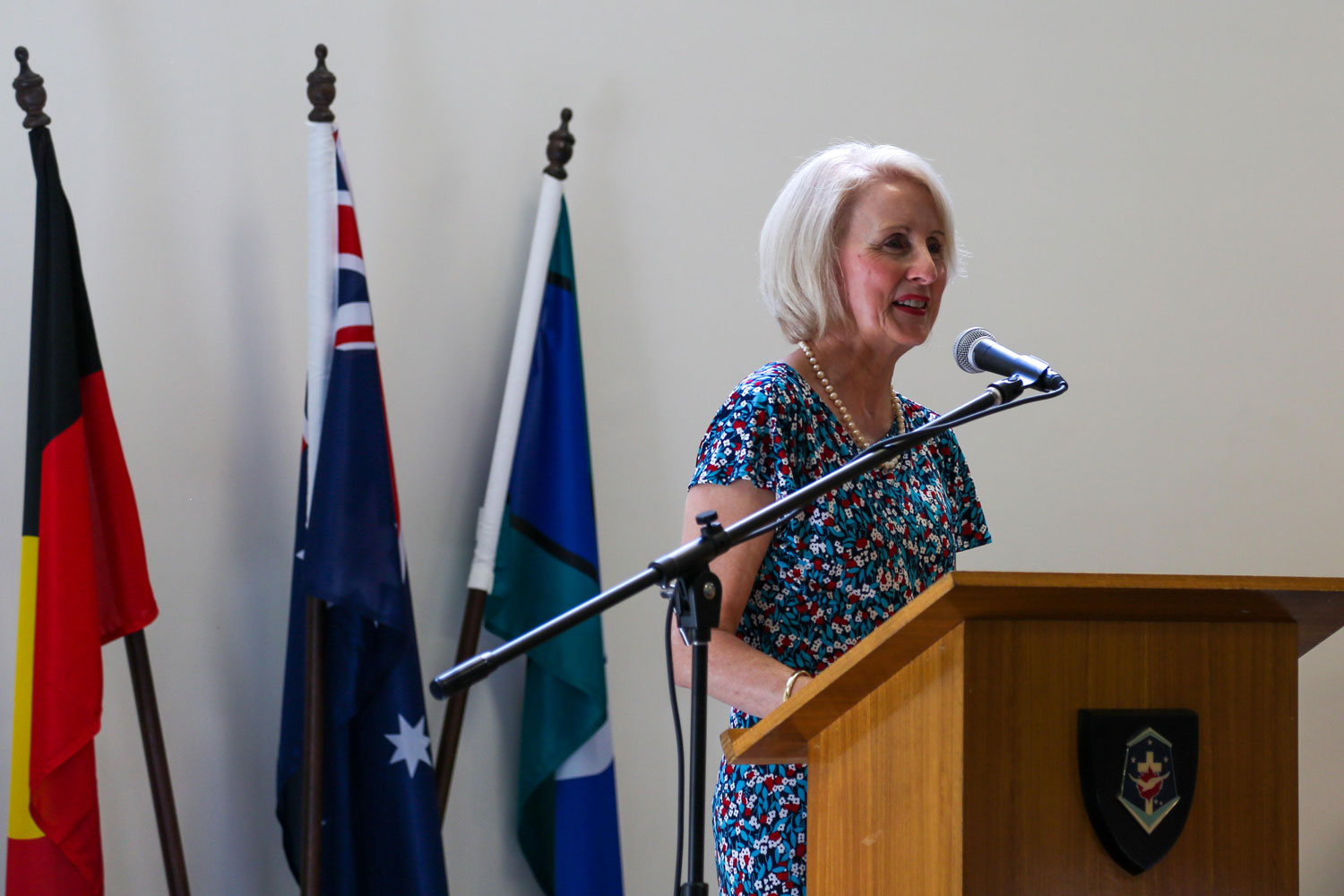 一位妇女站在讲客澳大利亚语、原住民语和托雷斯海峡岛民旗帜后