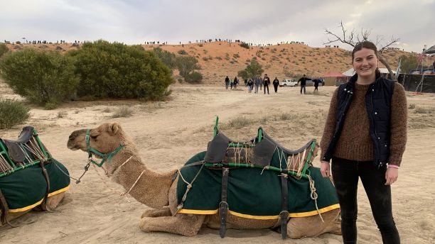 骑着骆驼坐在地上的女人