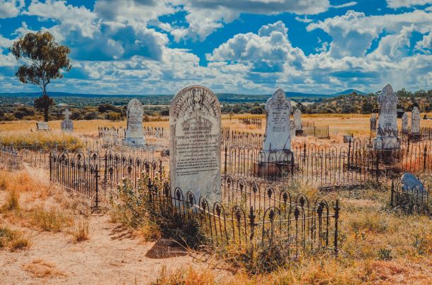 公墓里的巨大的历史墓碑，周围是沙子和干草，背景是明亮的蓝天和云彩。