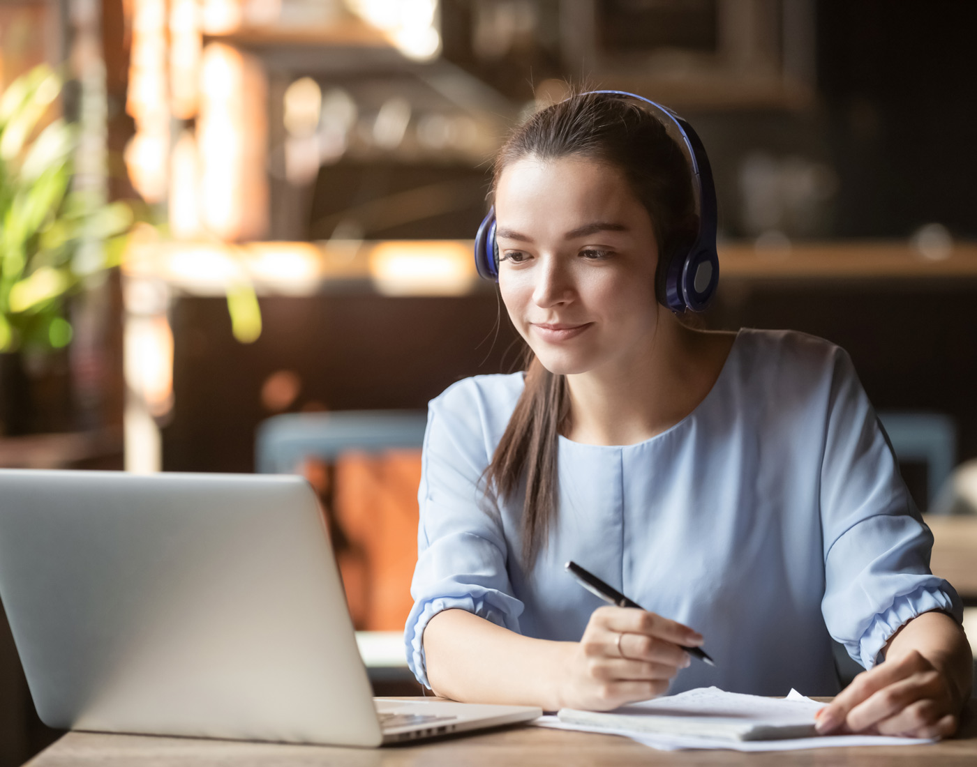 女学生戴着耳机，坐在笔记本电脑前在线学习
